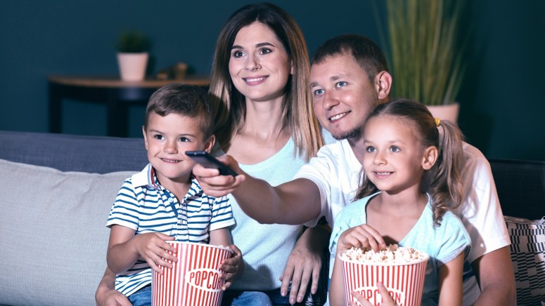 Happy family eating popcorn while watching TV in evening