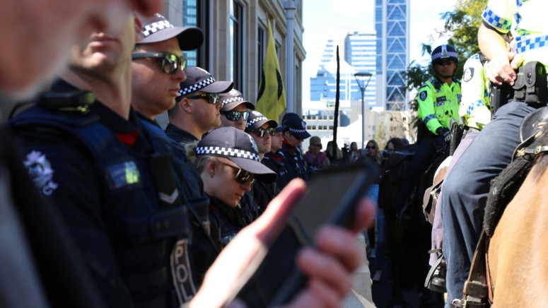 Man with Smartphone with Police in Background